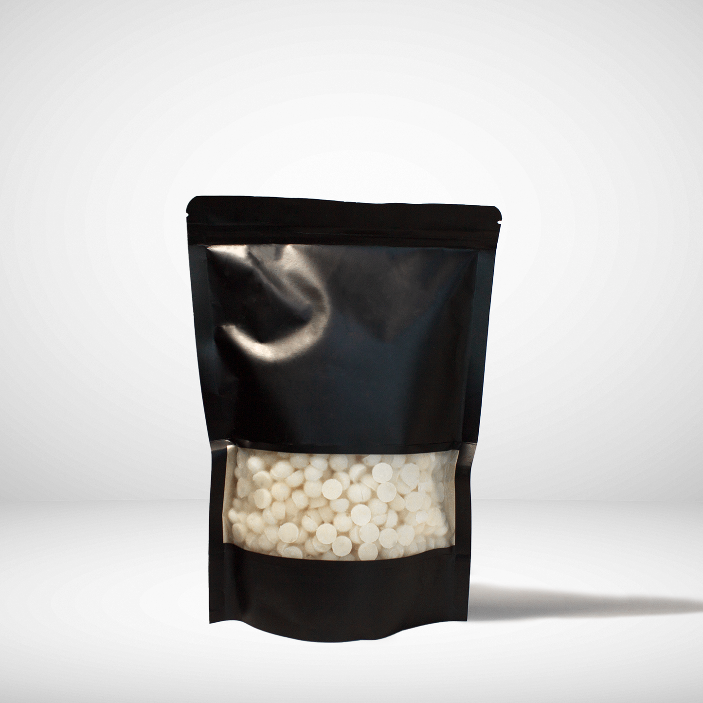 Black stand-up pouch with white beeswax pellets on a white background