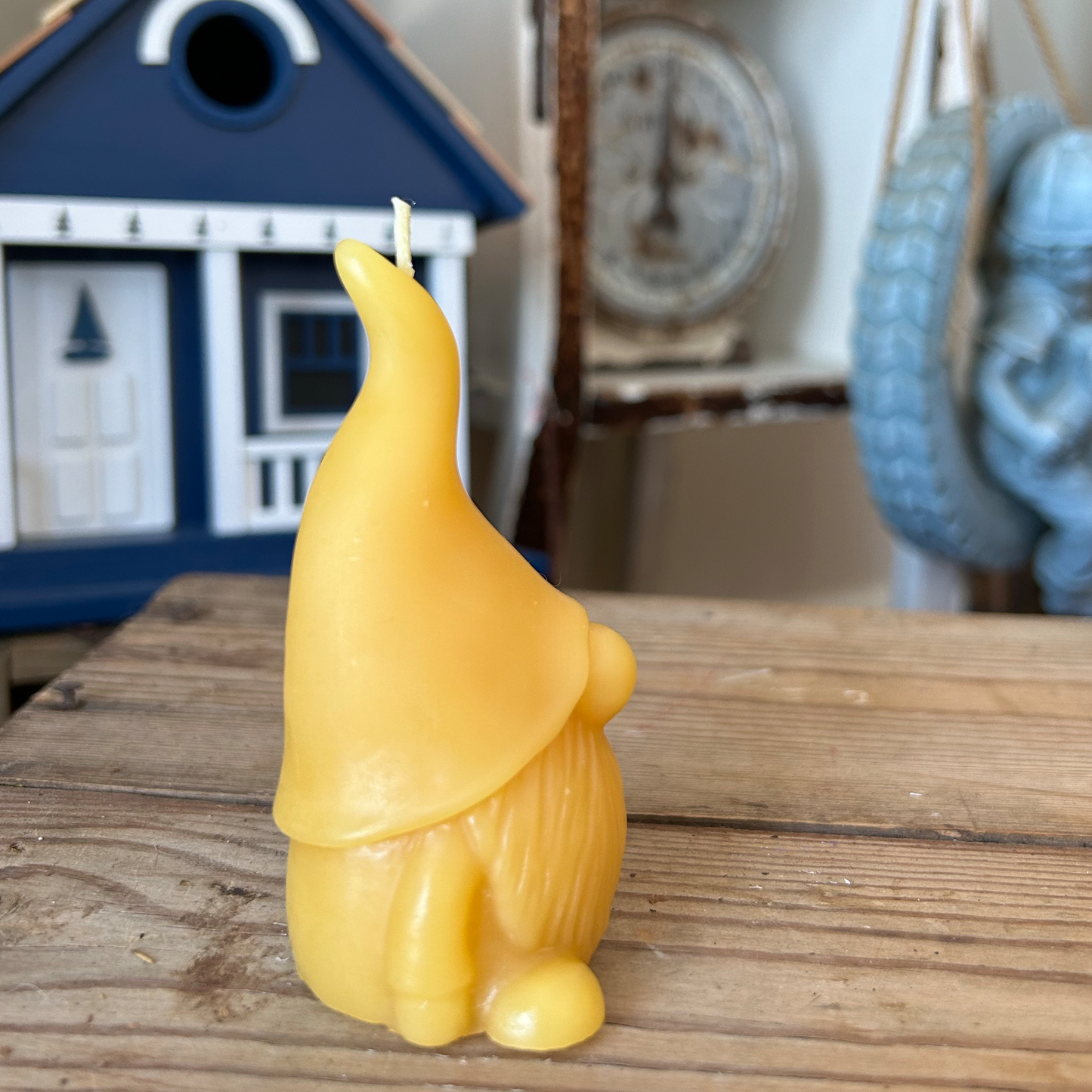 Yellow beeswax candle shaped like a gnome on a wooden surface with a blurred background