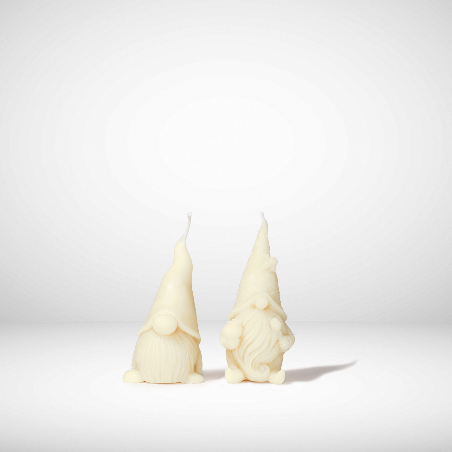 Two white beeswax gnome-shaped candles on a light gray background