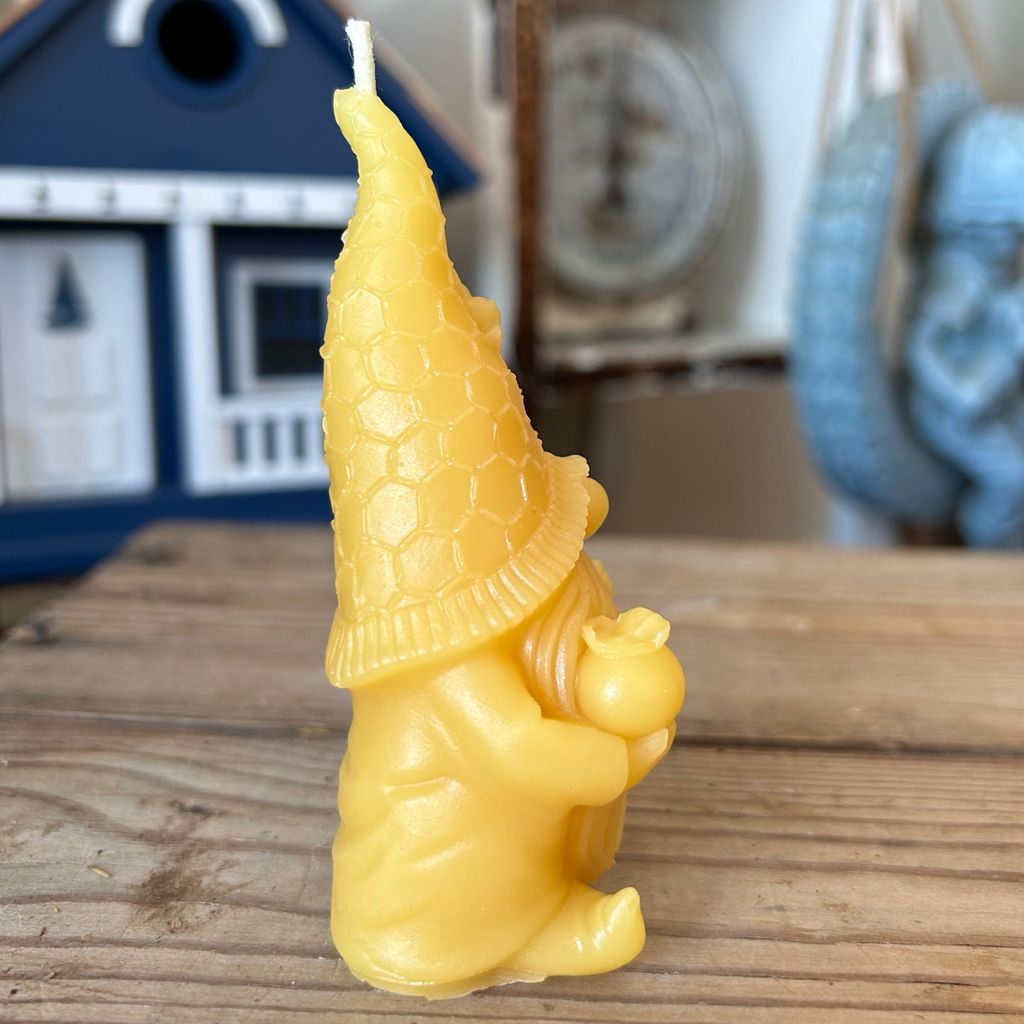 Yellow gnome beeswax candle on a wooden surface with a blurred background