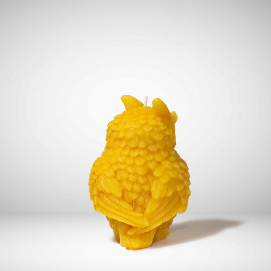 Yellow beeswax candle shaped like an owl on a white background