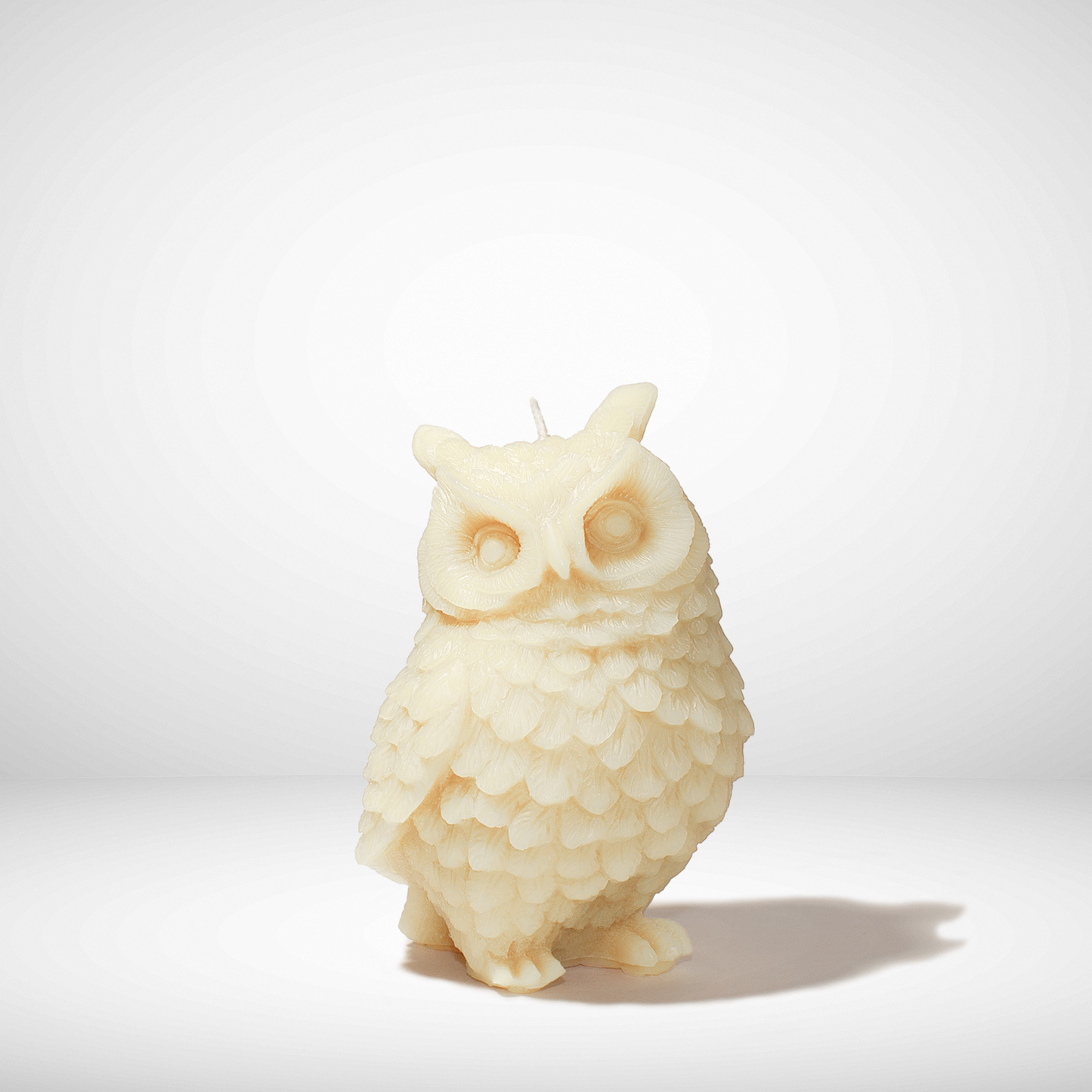 White owl-shaped beeswax candle on a white background