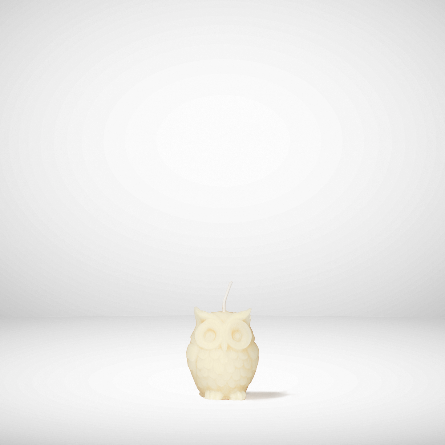 White owl-shaped beeswax candle on a white background