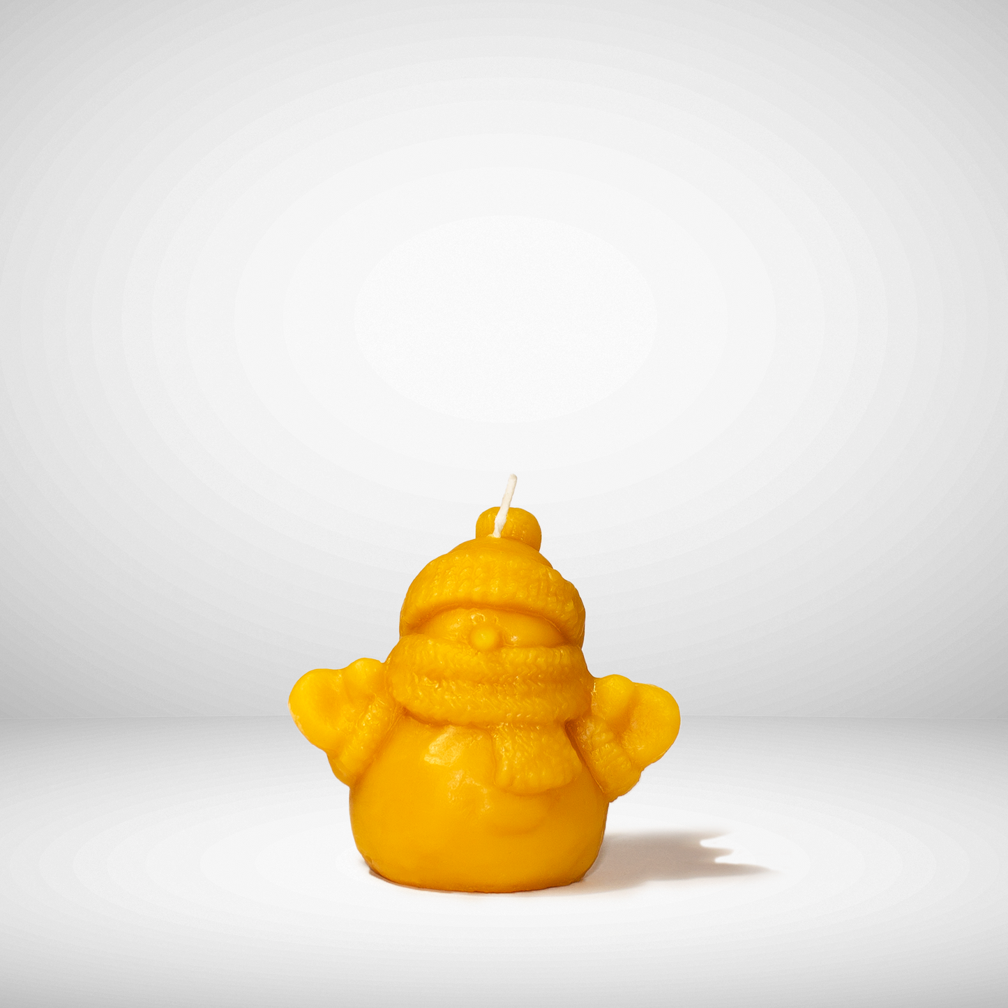 Yellow beeswax Candle that is snowman with a hat and scarf