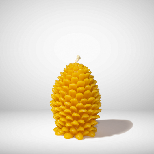 A yellow beeswax candle shaped like a pinecone, set against a neutral background