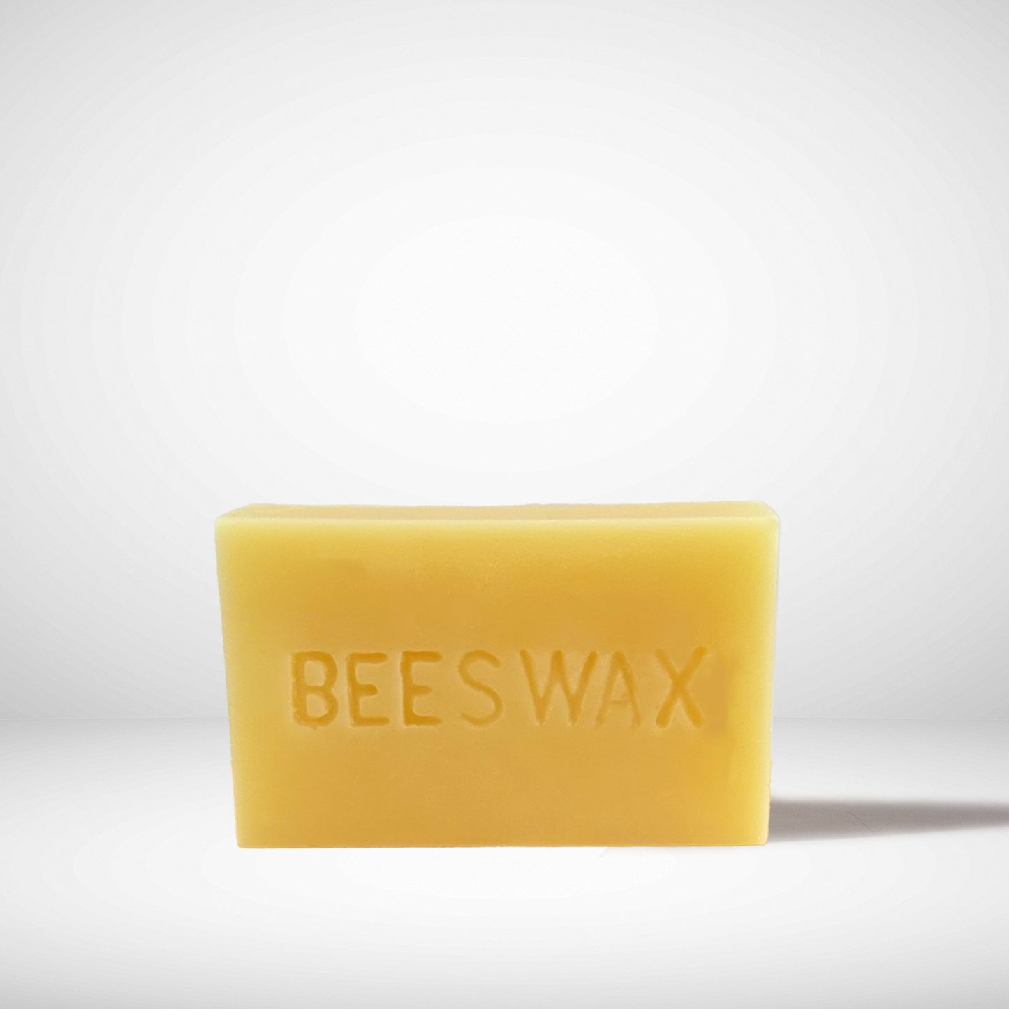 A yellow brick of pure Canadian beeswax with the words 'BEESWAX' embossed on the surface.