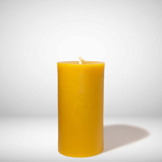A single yellow beeswax pillar candle on a white background.