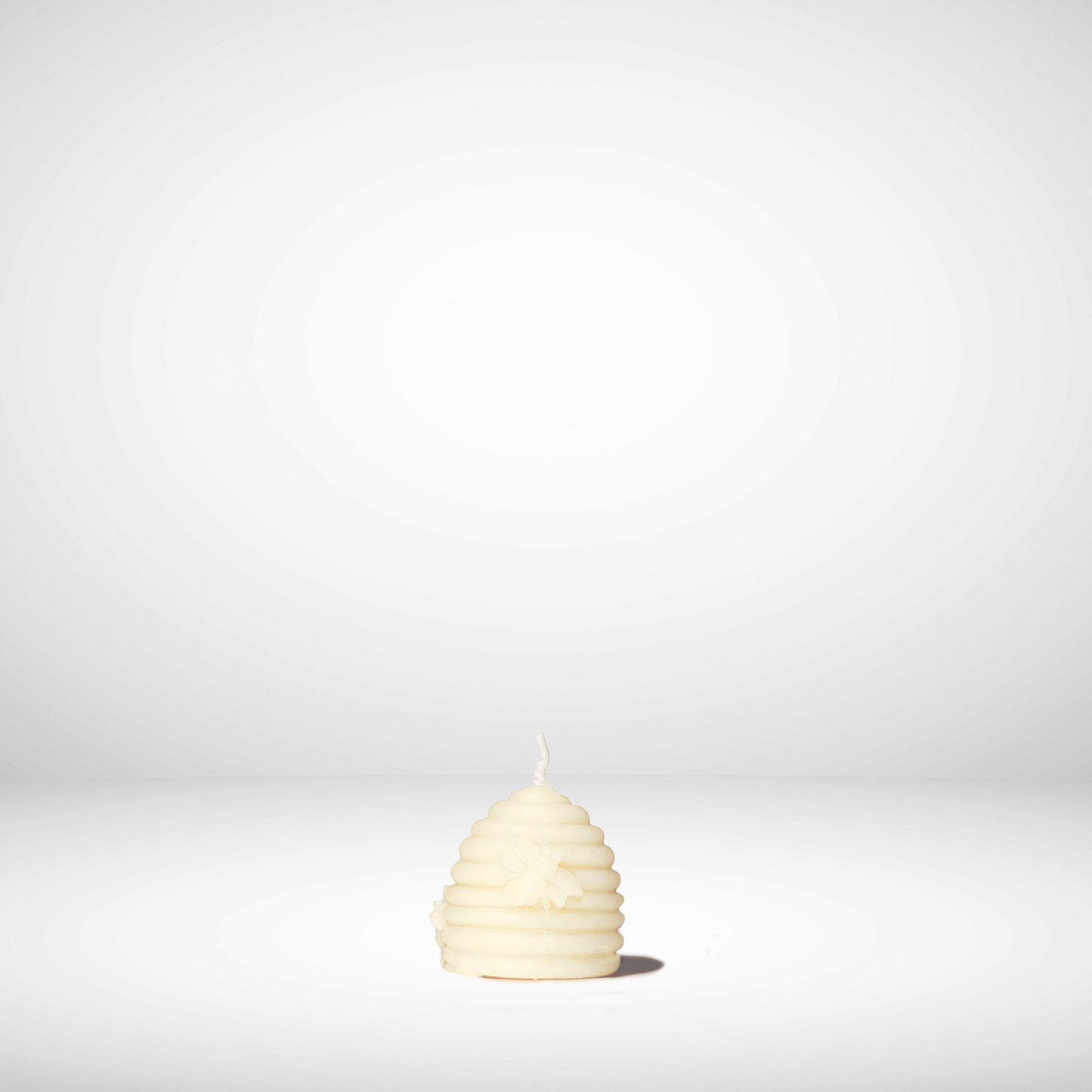 Beehive-shaped beeswax candle on a white background