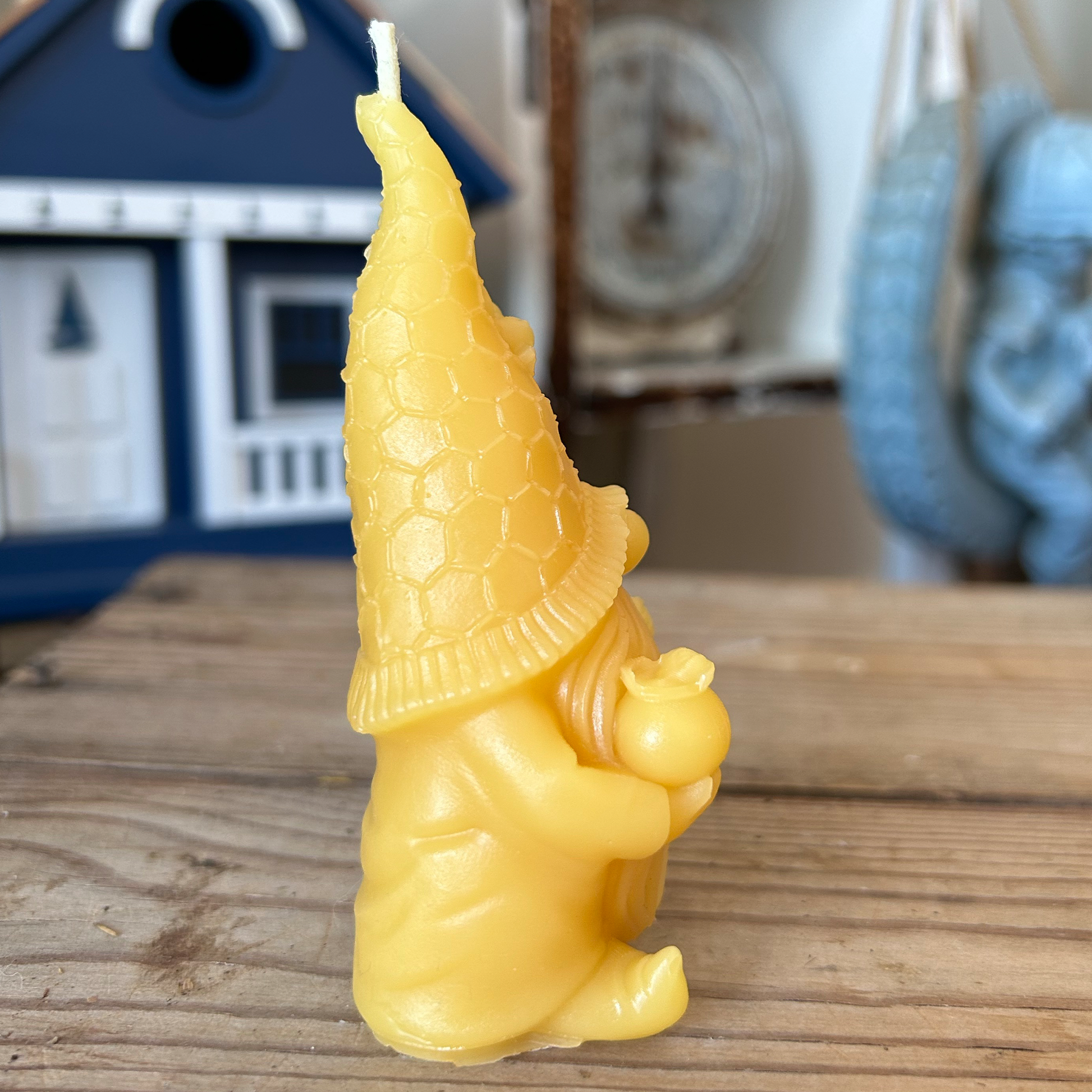 Yellow gnome beeswax candle on a wooden surface with a blurred background