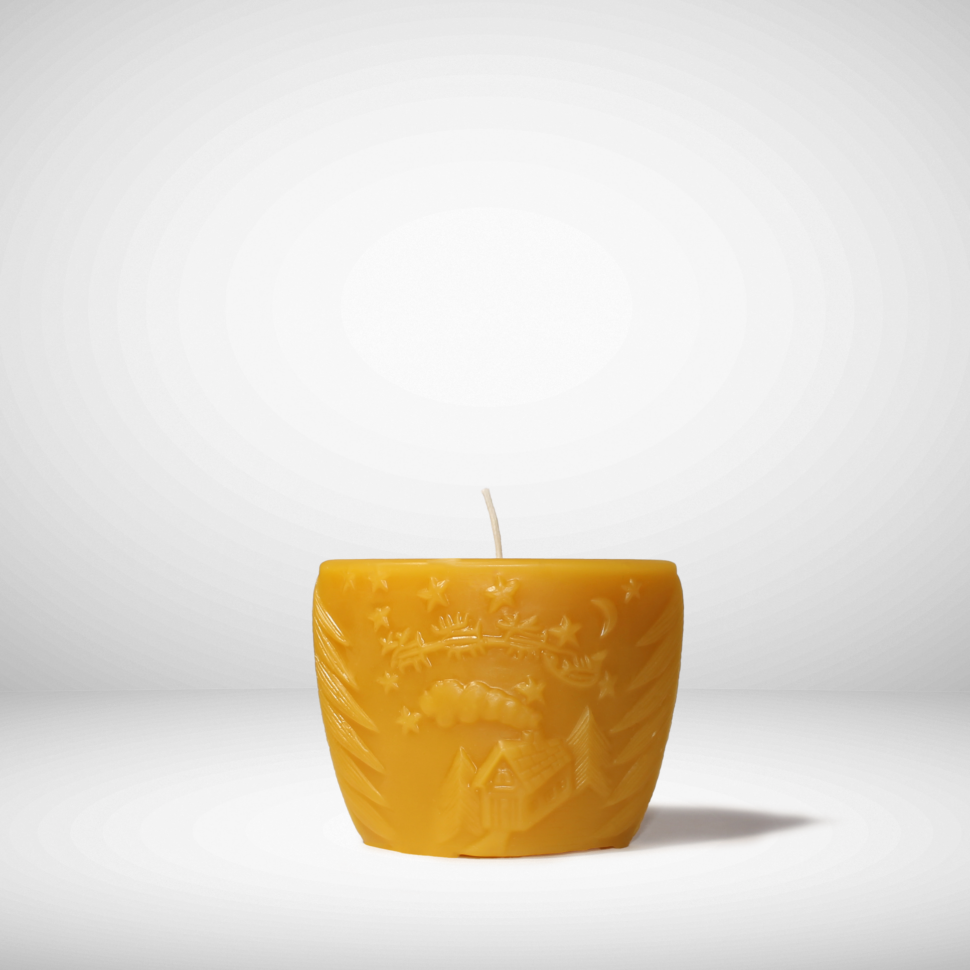Yellow embossed candle on a white background with a little Christmas scene on it. 