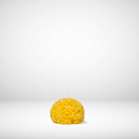A spherical beeswax candle with a floral pattern, predominantly yellow in color, against a white background.