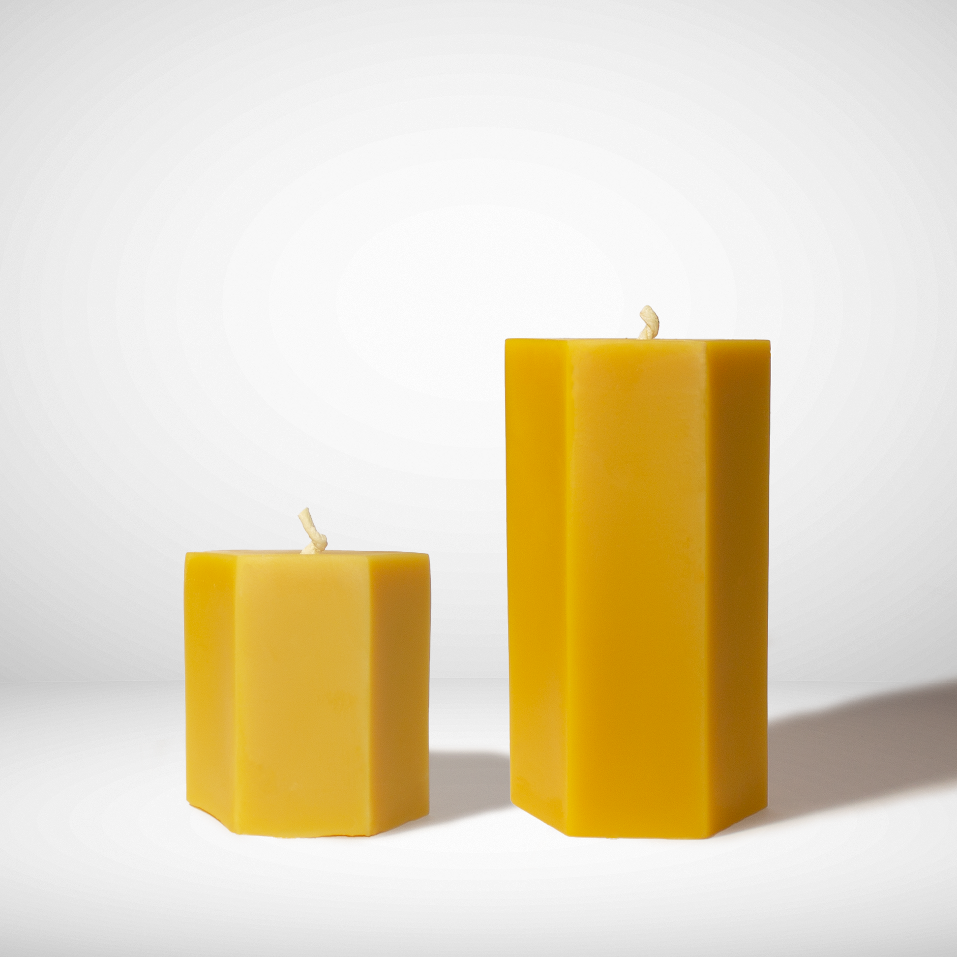 Two hexagonal beeswax candles on a white background