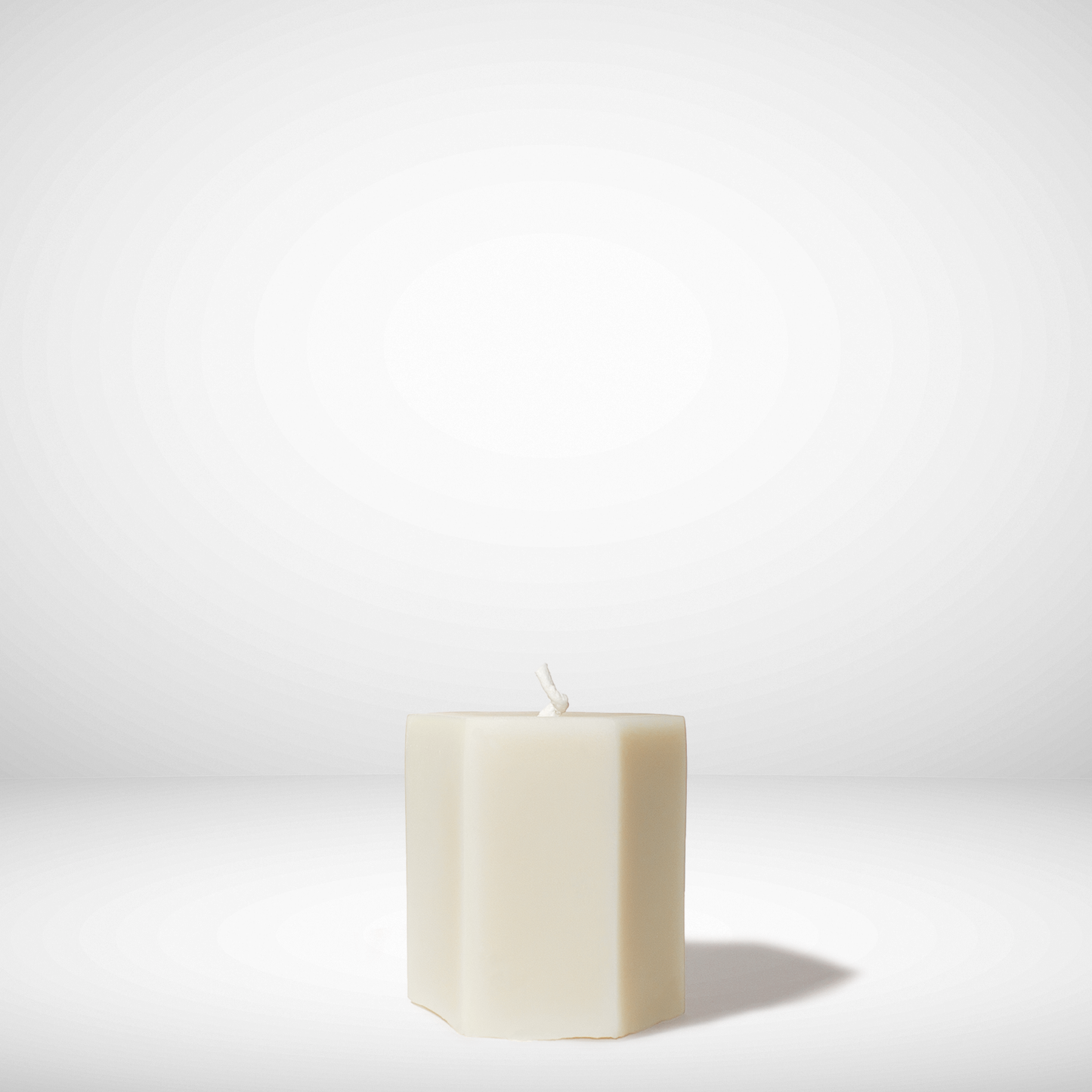 White hexagonal beeswax candle on a white background