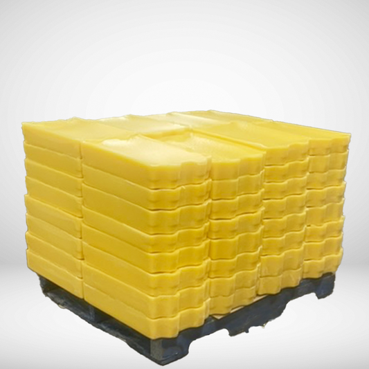 A large block of yellow Canadian beeswax rendered and stacked on a pallet.