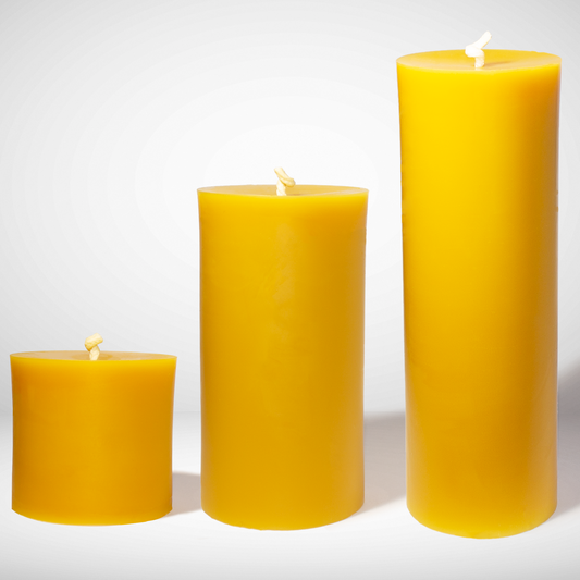 Three yellow beeswax candles of different sizes on a white background
